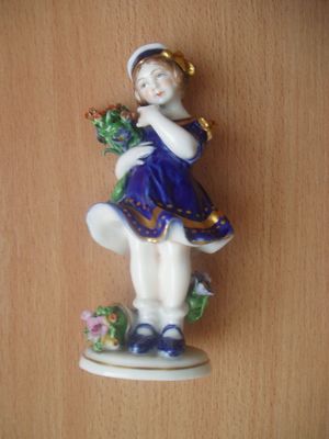 Porcelánová soška dívky s květy.